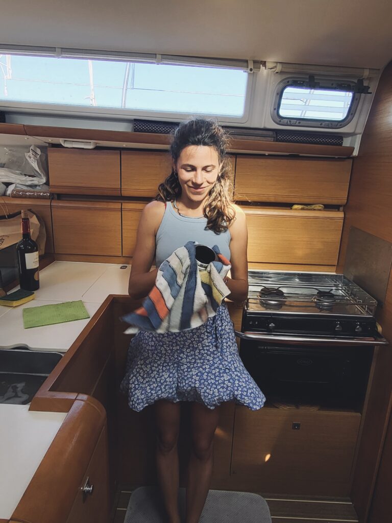 Erica smiling and drying a moka in the boat's kitchen